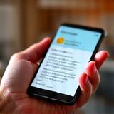 Two hands holding a smartphone displaying a positive review, representing client feedback.