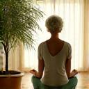 Woman doing gentle yoga stretches in a sunlit room, representing movement and exercise prescription.